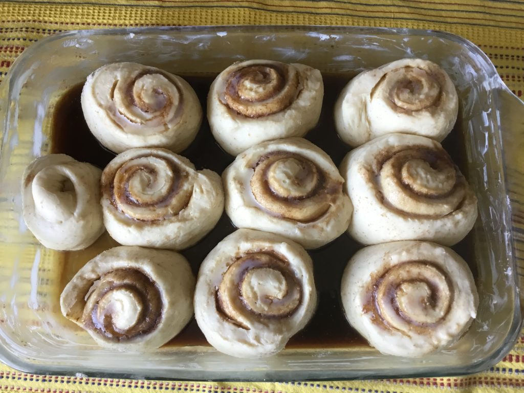 A glass pan willed with cinnamon rolls.
